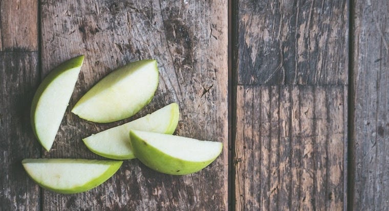 sliced green apples on wood table