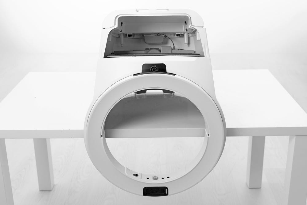 Litter-Robot unit turrned upside down with bezel hanging over the end of a table