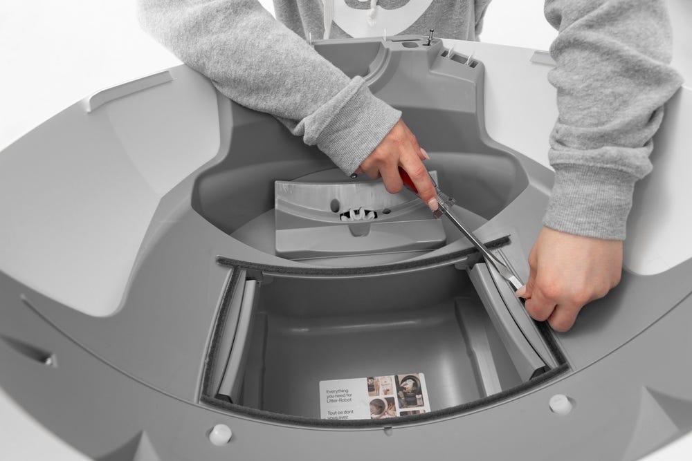 Waste port seal strip being removed with flat head screwdriver