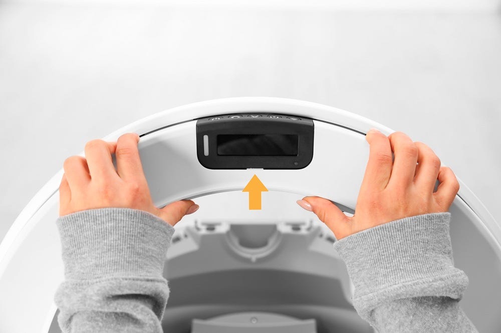 Closeup of bezel being reinstalled with two hands. Arrow pointing towards control panel