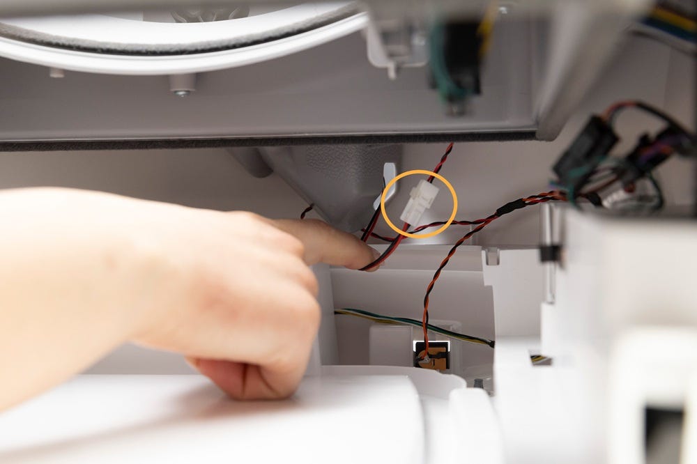 Inside of base with a finger pointing to the wire connectors