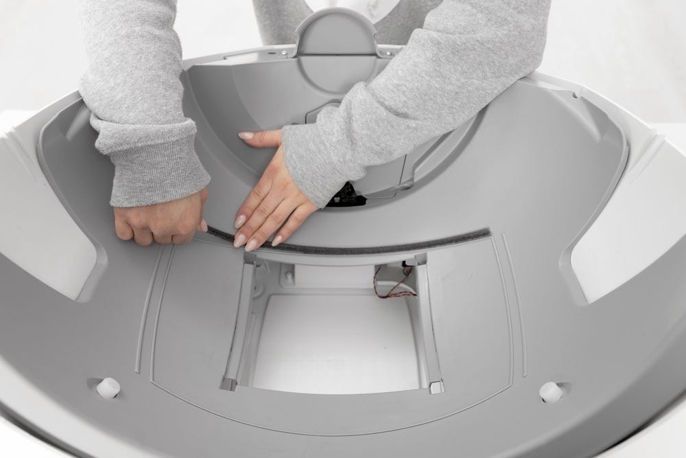 Litter-Robot base with seal strip being applied along back edge of waste drawer opening