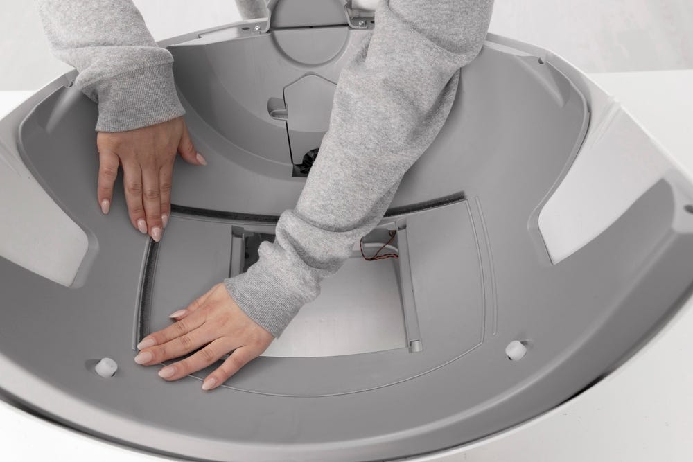 Litter-Robot base with seal strip being applied along the left side of the waste drawer opening