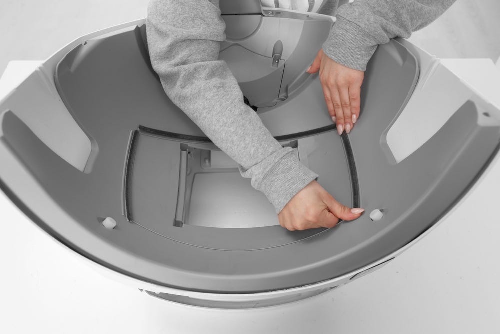 Litter-Robot base with seal strip being applied along the right side of the waste drawer opening