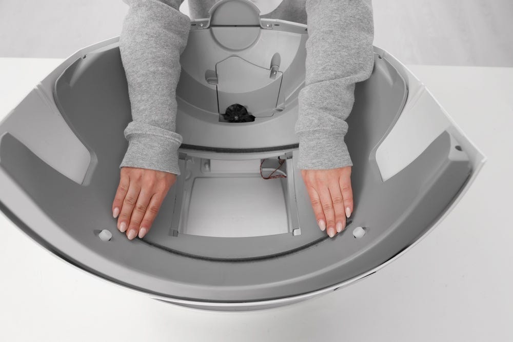 Litter-Robot base with seal strip being applied along the front edge of the waste drawer opening