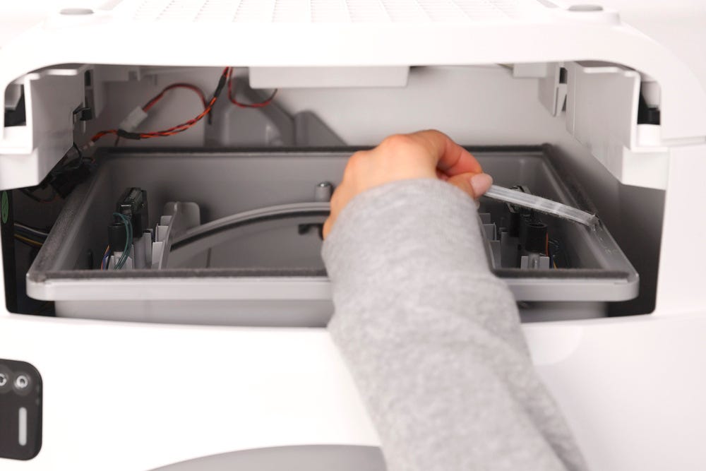 Litter-Robot base upside down with drawer removed and seal strips being peeled away